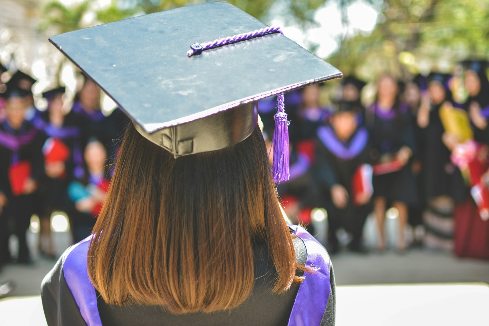 A graduate in a cap and gown seen from behind at a ceremony