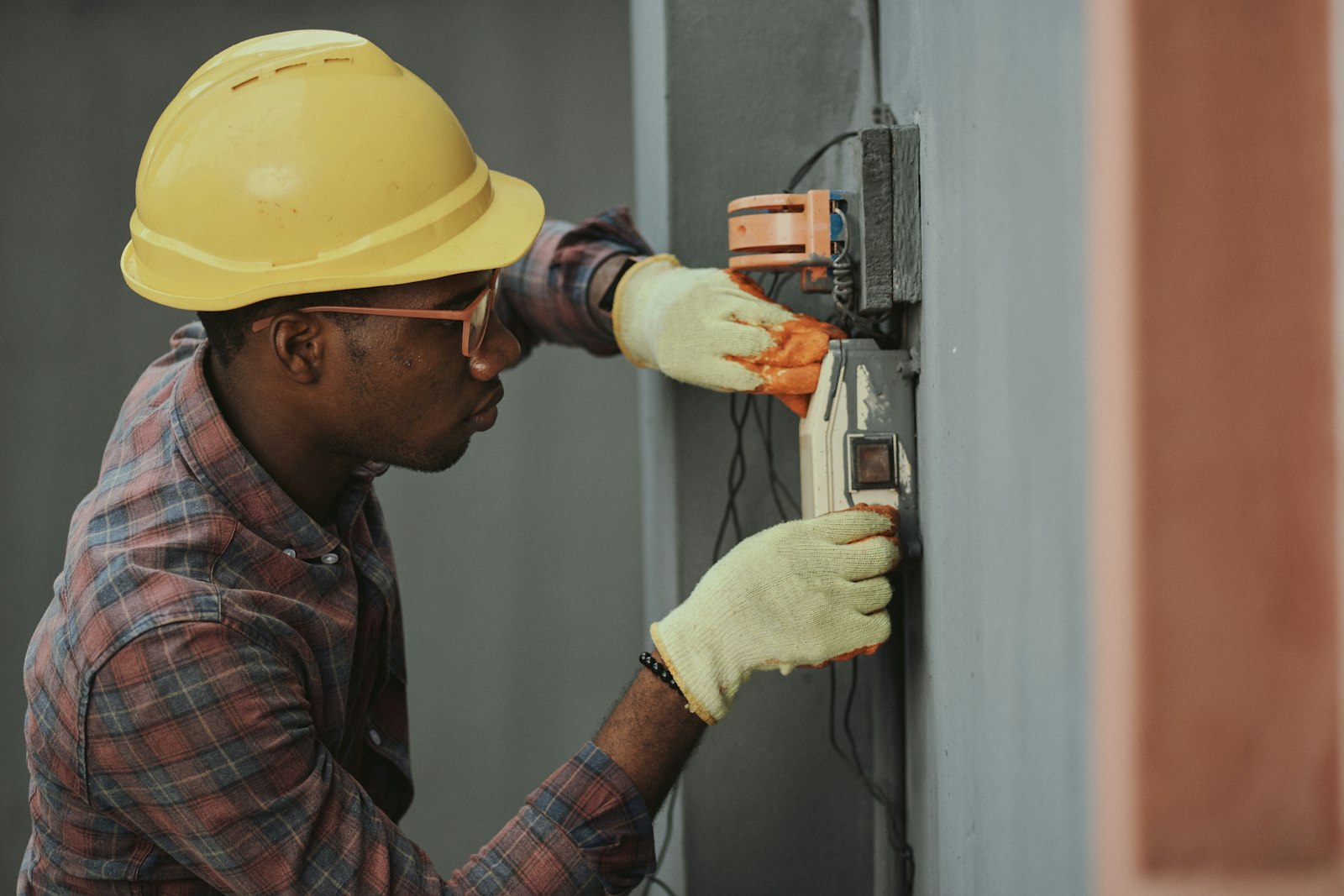 A young electrician in a hard hat working on wiring