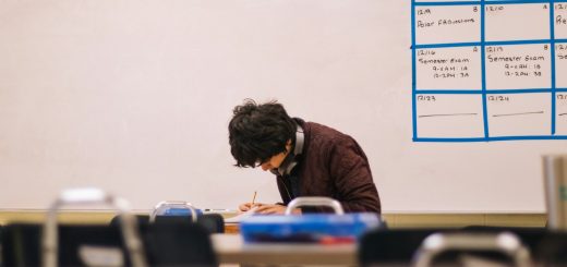 A student writing at a desk in a classroom