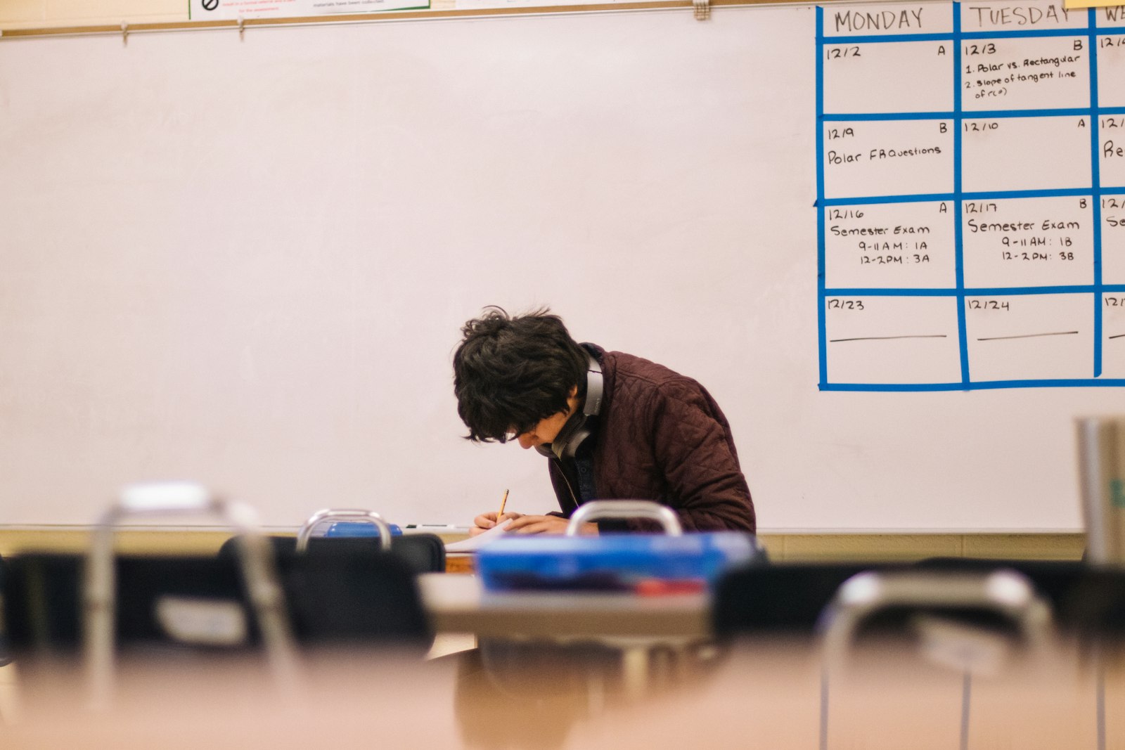 A student writing at a desk in a classroom