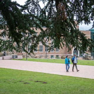 Students walking along a path past a campus building
