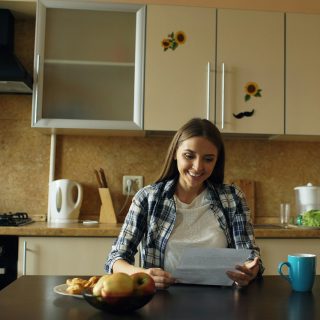 A woman reading study notes at a kitchen table with a cup of coffee