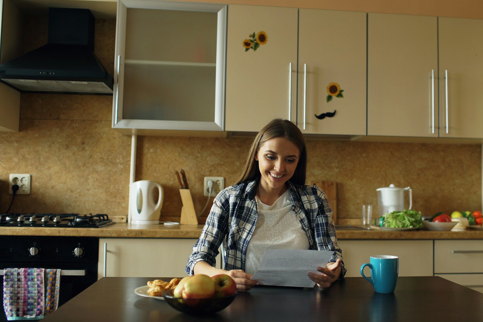 A woman reading study notes at a kitchen table with a cup of coffee
