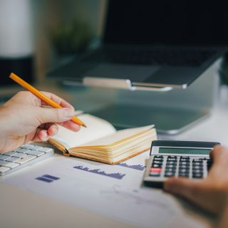 Hands working out a budget with a calculator and a notebook