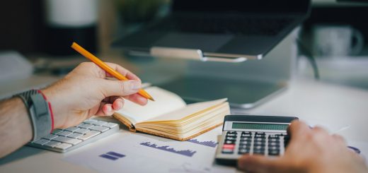Hands working out a budget with a calculator and a notebook