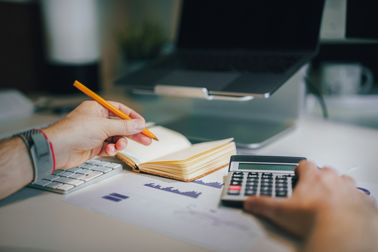 Hands working out a budget with a calculator and a notebook