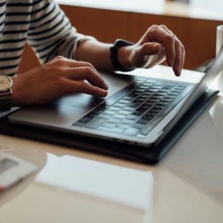 Hands typing on a laptop at a desk